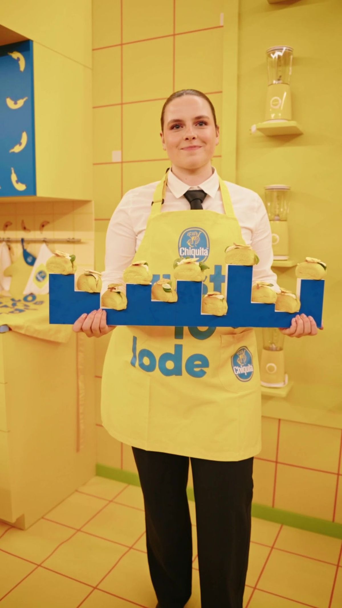 Cameriera con divisa logata Chiquita offre mini bao gialli salati con originale vassoio blu al catering  allestito da Zeta Eventi