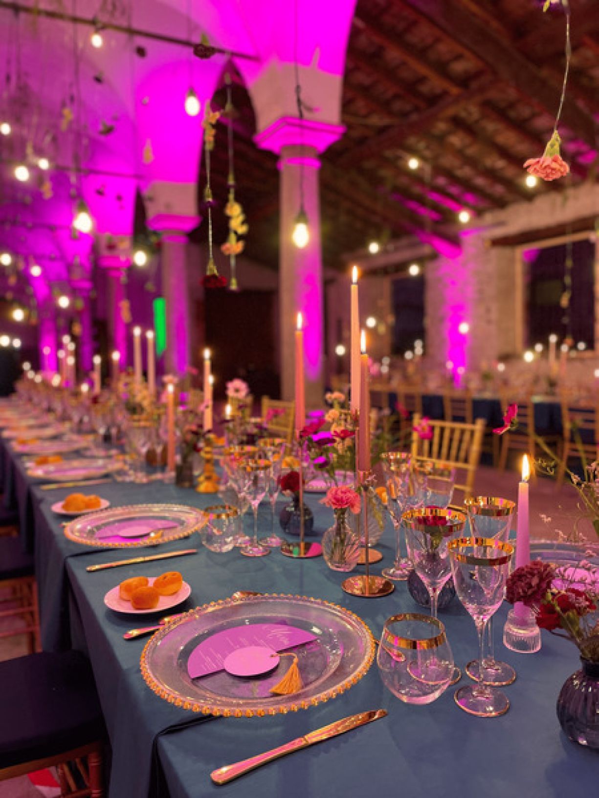 Sala a colonne con light designer fucsia per tavola rosa e oro