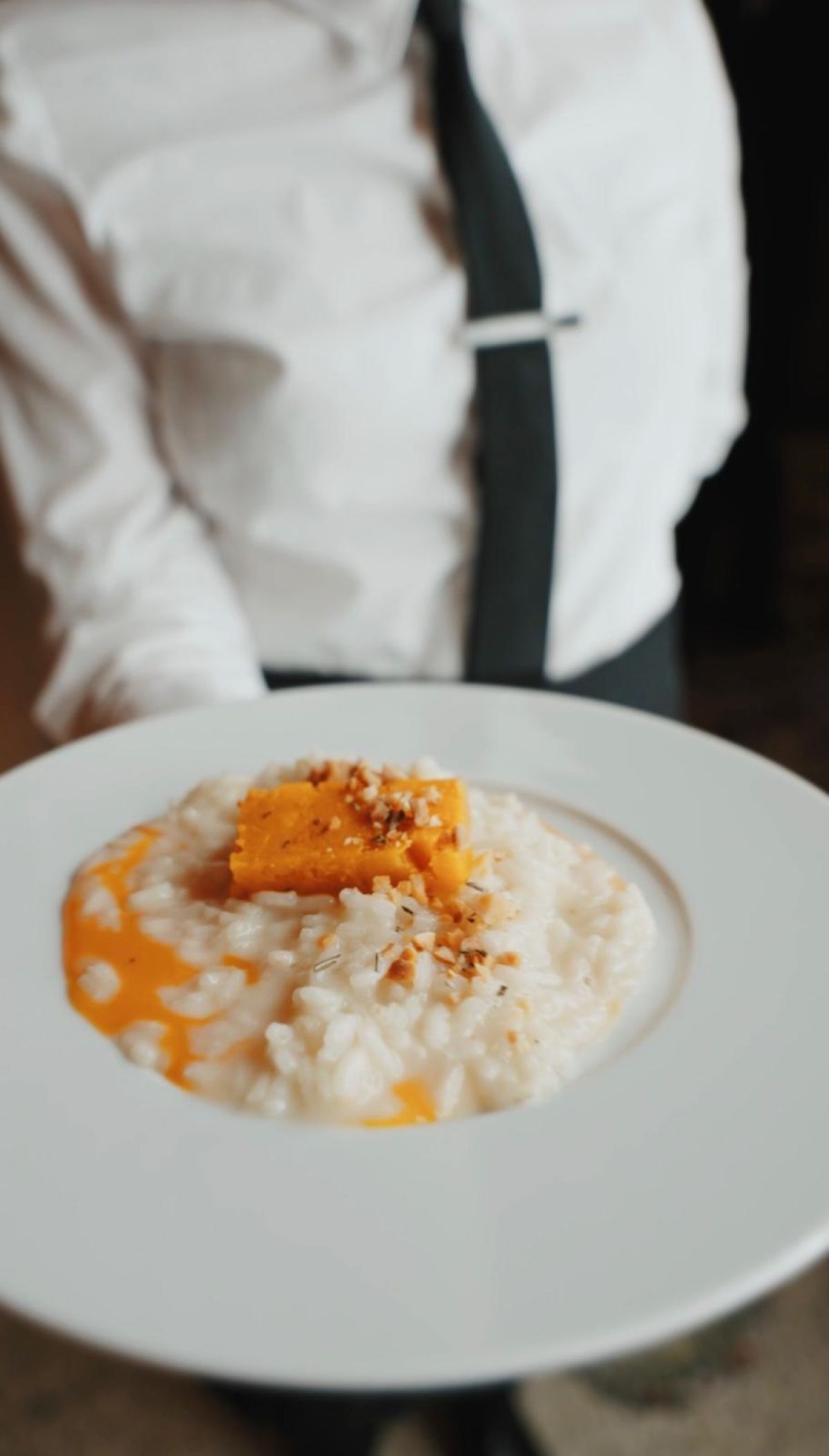 Cameriere serve risotto alla milanese come piatto caldo al cocktail in Galleria Meravigli Milano