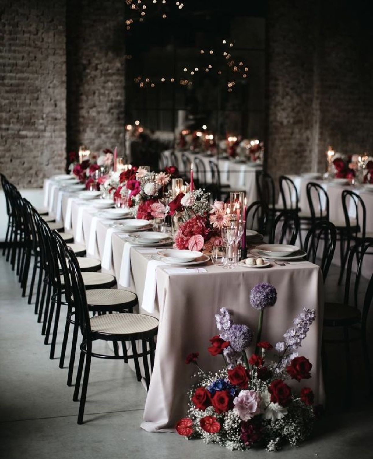 Composizione floreale rosa, rosso, viola in testa ai tavoli per matrimonio al Castello di Piovera di Zeta Eventi Milano
