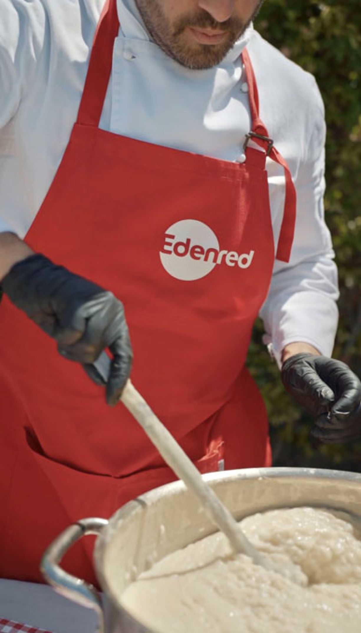 Chef con grembiule rosso e logo Edenred prepara risotto per light lunch evento