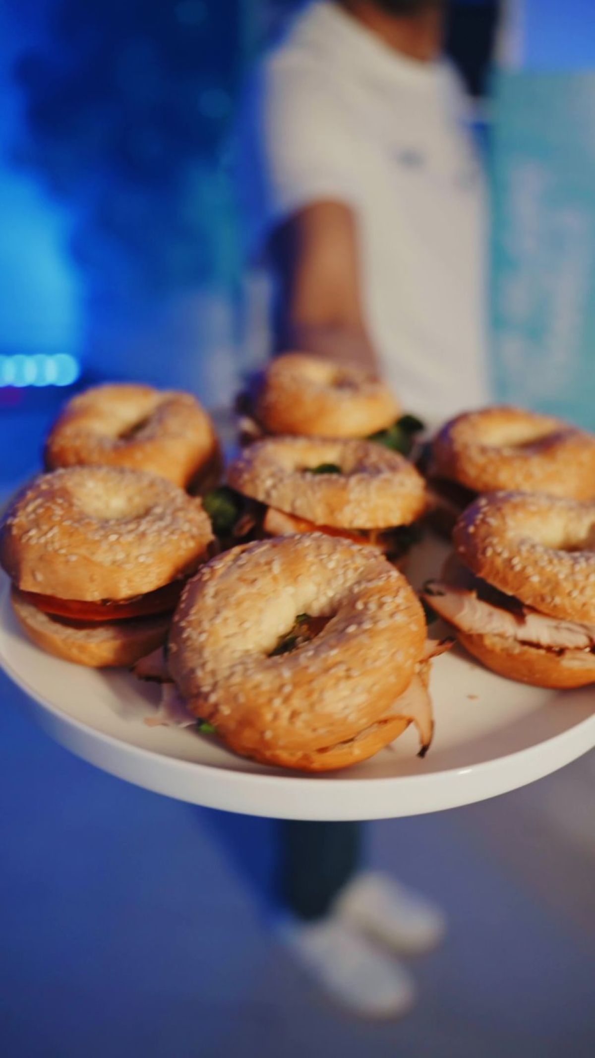 Cameriere serve vassoio di bagels farciti per l’aperitivo alla festa di compleanno in piscina coperta villa privata