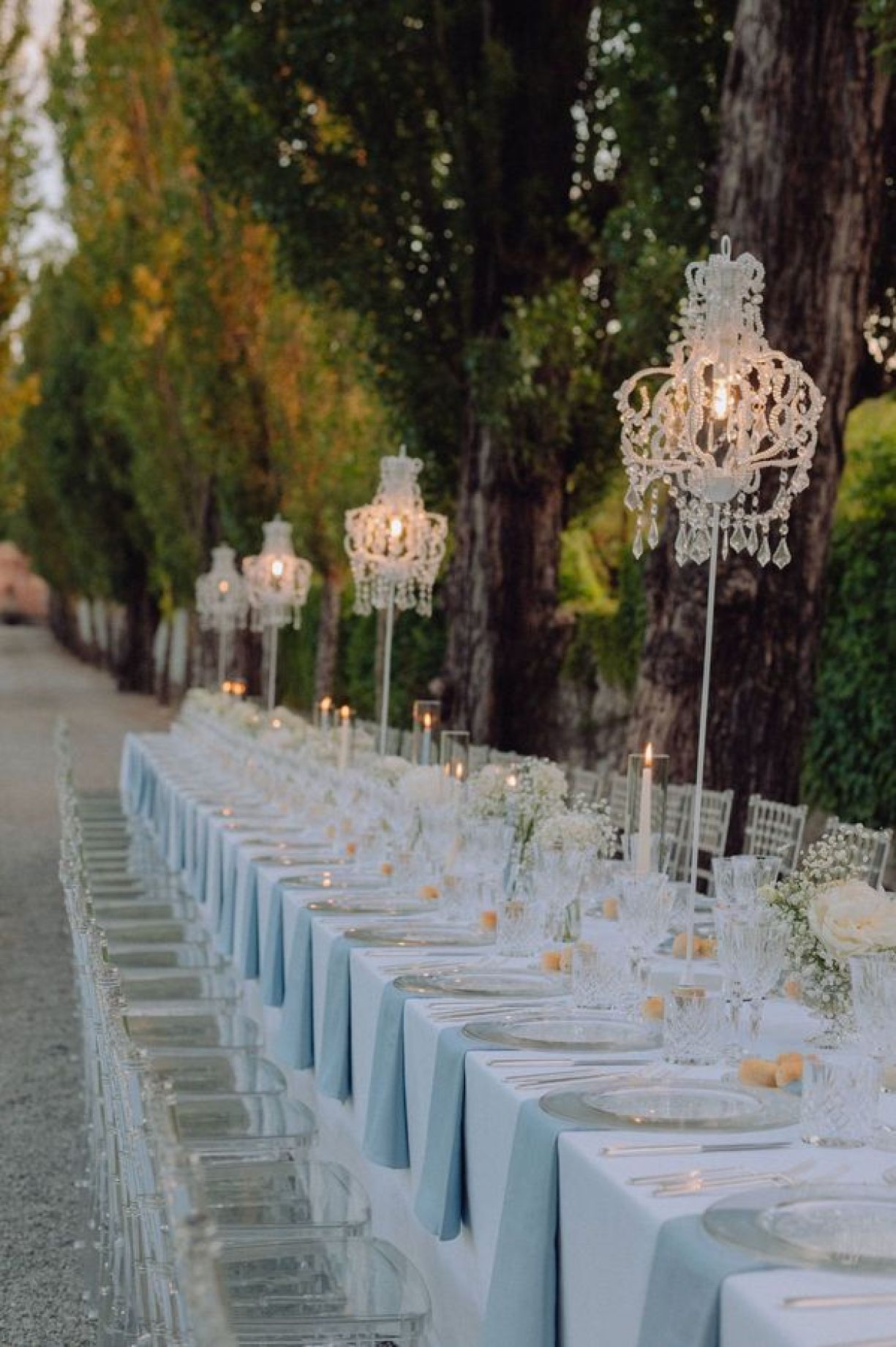 Tavola wedding dinner all'aperto bianco e trasparente con lampade alte di cristallo